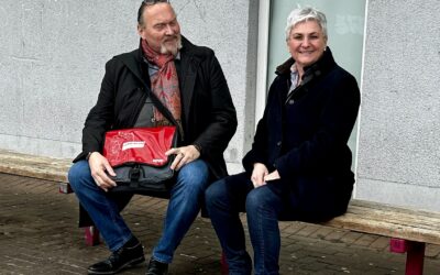 Carmen Brönner testet mit Thomas Hammer die niedrigen Sitzbänke am Busbahnhof
